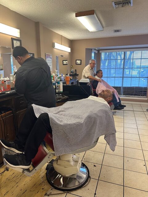 Attractive Muscled Bearded Barber Cutting Handsome Young Customer Beard At The Barber Shop